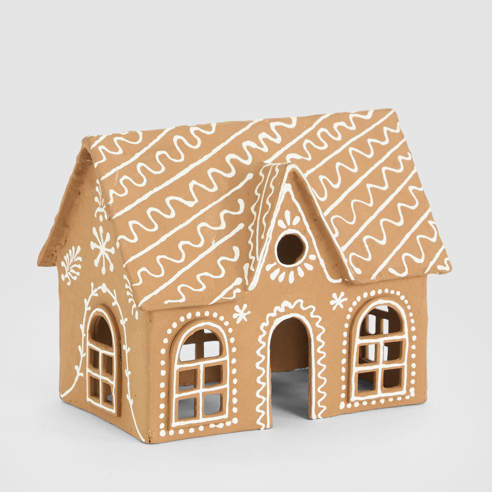 Tan paper mache gingerbread cottage with white icing-style lines, arched windows and a central doorway