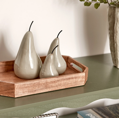 Small, Medium and Large glossy green ceramic pear sculptures arranged on a wooden tray