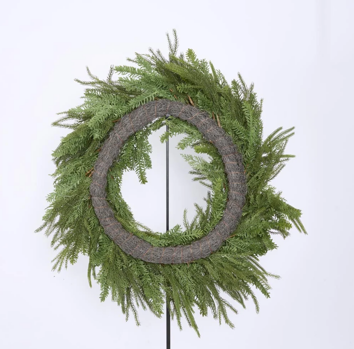 Mixed green wreaths styled with red decorations above a Christmas mantel