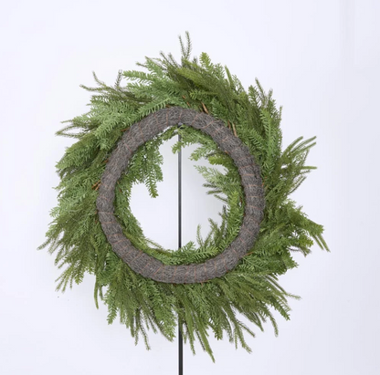Mixed green wreaths styled with red decorations above a Christmas mantel