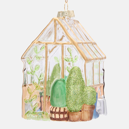 Side view of the glass greenhouse decoration showing green plants and gold window framing