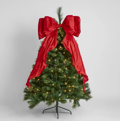 Red satin bow and trailing tails styled on an unlit green Christmas tree