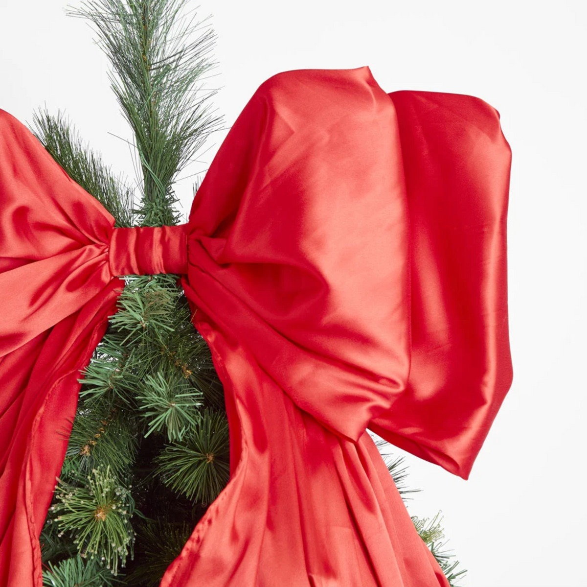 Christmas room display with red satin bow atop a decorated tree, red ornaments and wrapped gifts