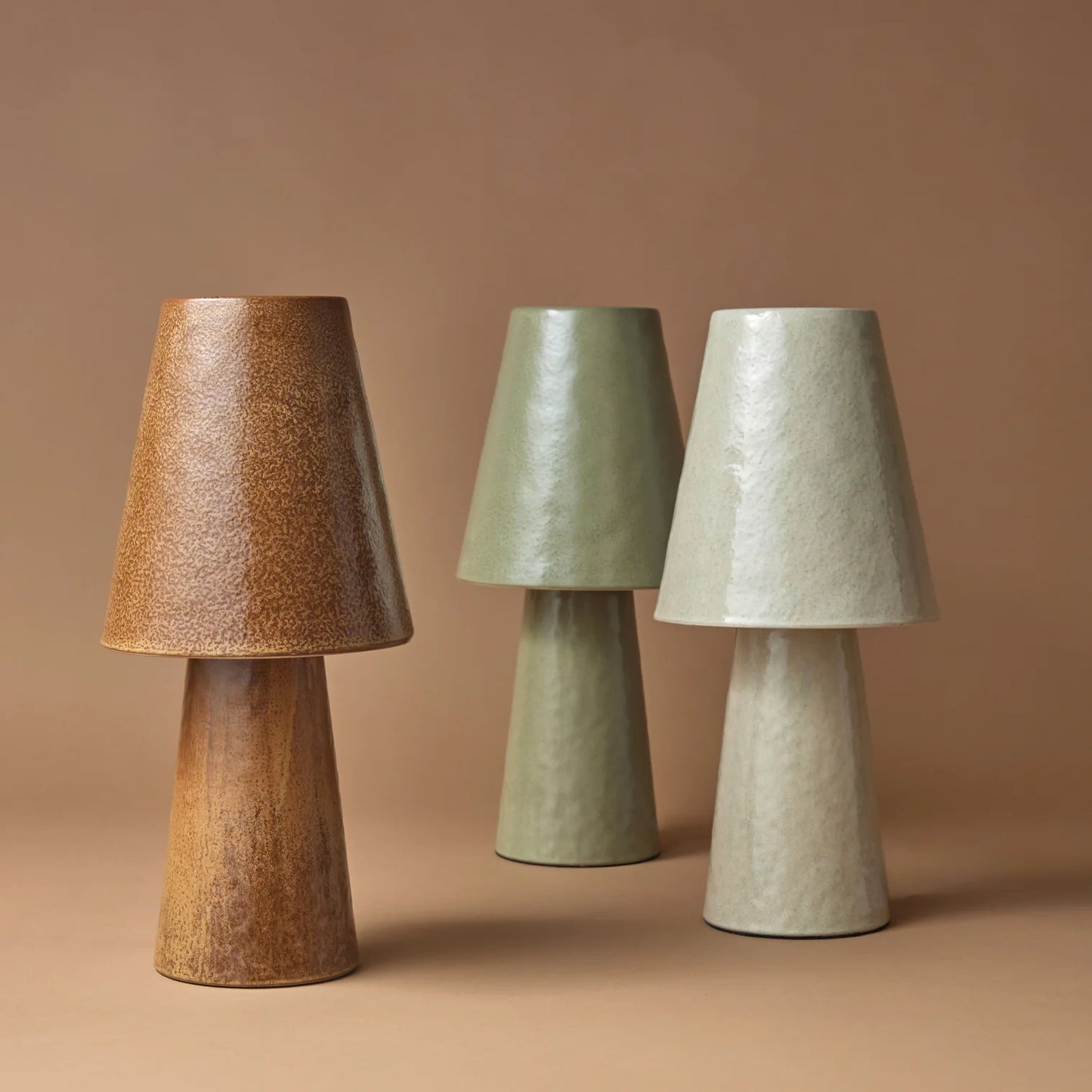 Three textured ceramic table lamps in rust, sage green and ivory